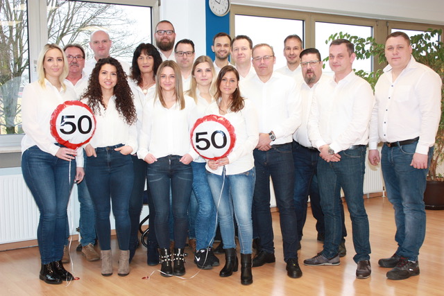 Es handelt sich hierbei um ein Gruppenfoto der häwa Niederlassung Duisburg in weißen Hemden. Man sieht außerdem zwei Luftballons mit der Zahl 50.